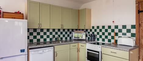 A compact kitchen with a dishwasher, microwave, stove, and a toaster.