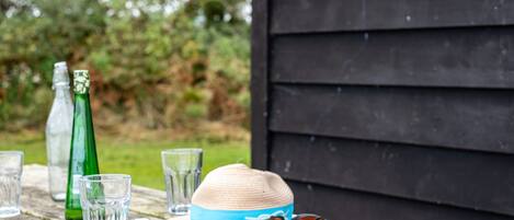 Un banc en bois sur lequel sont posés un chapeau, des lunettes de soleil, une carte pliée et une bouteille.