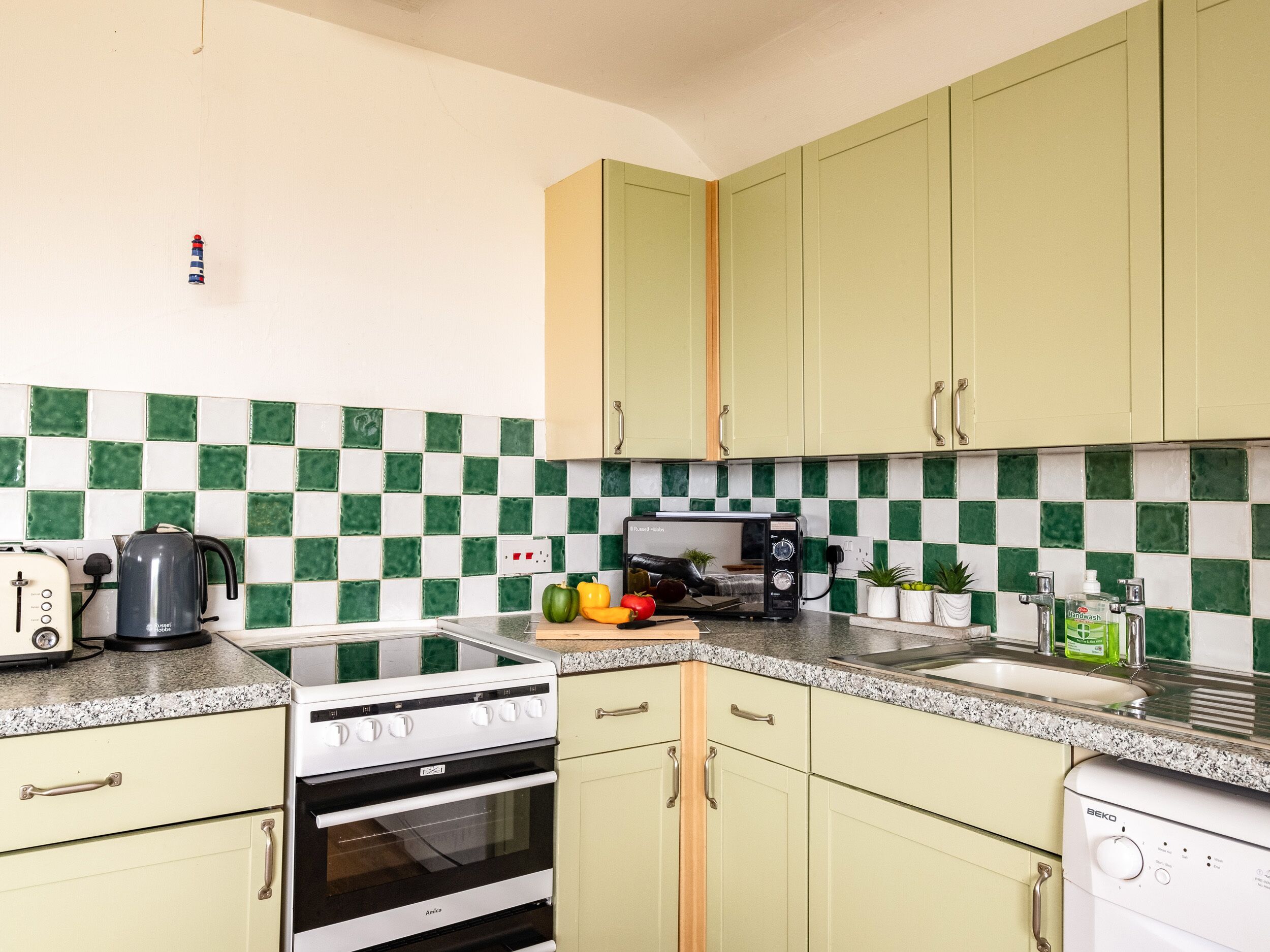 A kitchen with green cabinets, a white stove, and a sink.