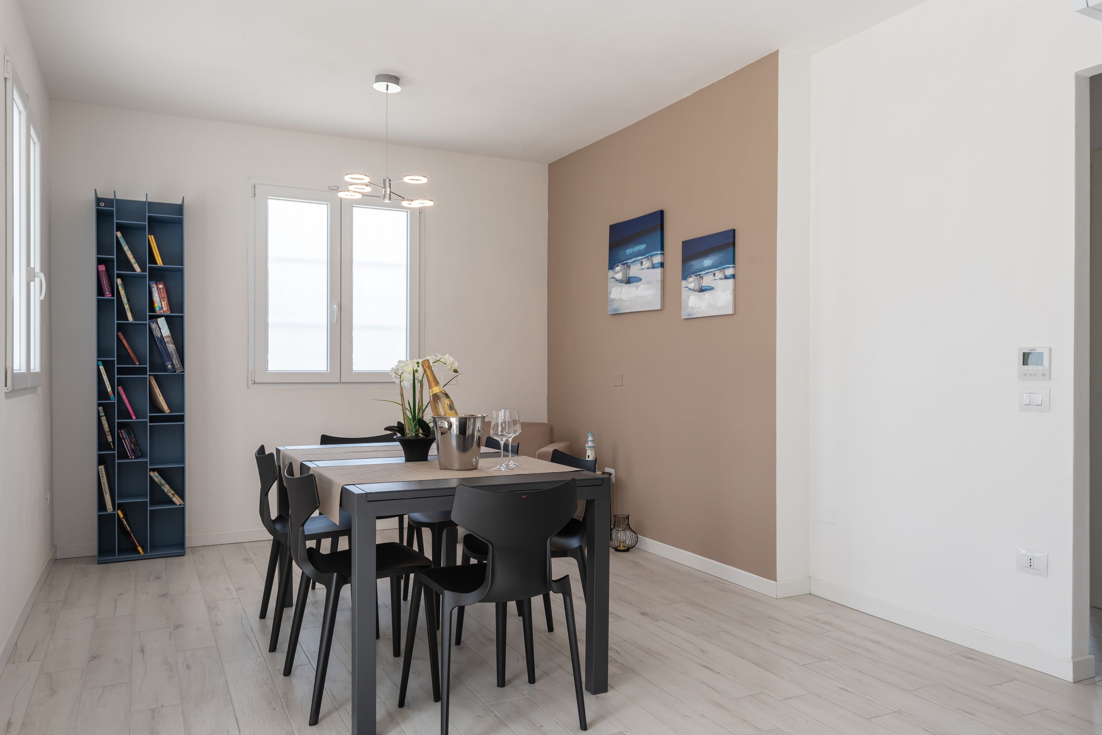 Un coin repas comprenant une table, des chaises, une bibliothèque et deux tableaux accrochés au mur.