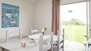 Un comedor con una mesa, sillas y un cuadro de una escena costera.