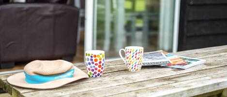 A wooden table with a hat, a polka-dotted mug, and a magazine.