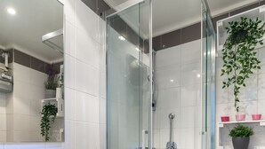 Un baño moderno con cabina de ducha de vidrio, un lavabo blanco y un espejo.