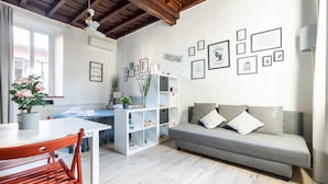 Una sala moderna con un sofá gris, una mesa de comedor de madera y una estantería blanca.