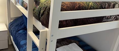 A bunk bed with a dinosaur-themed pillow and a white towel on the lower bunk.