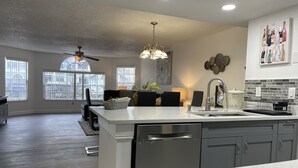 A modern kitchen with a central island, grey cabinetry, and a backsplash. - Fabulous Apartment near Disney (Kissimmee)