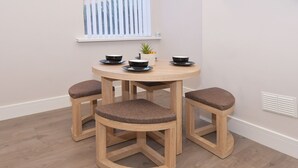 Una mesa redonda de madera con cuatro taburetes a juego, cada uno con asiento acolchado.