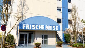 Un bâtiment avec un auvent bleu et une enseigne portant l’inscription « FRISCHEBRISE » au-dessus de l’entrée.