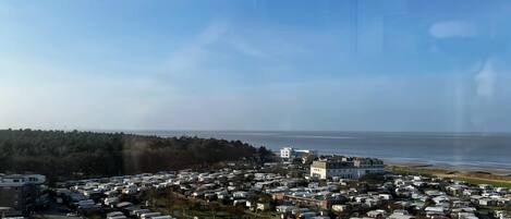 A large campground with numerous RVs and mobile homes, a few buildings, and a view of the ocean.