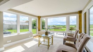 Une pièce spacieuse avec de grandes fenêtres, une table basse en verre et un canapé beige.