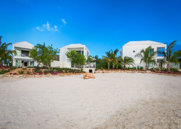 A beachfront property with modern white buildings, a sandy beach, and tropical landscaping. - SulMare at Sapodilla Bay Luxury villas (Providenciales)
