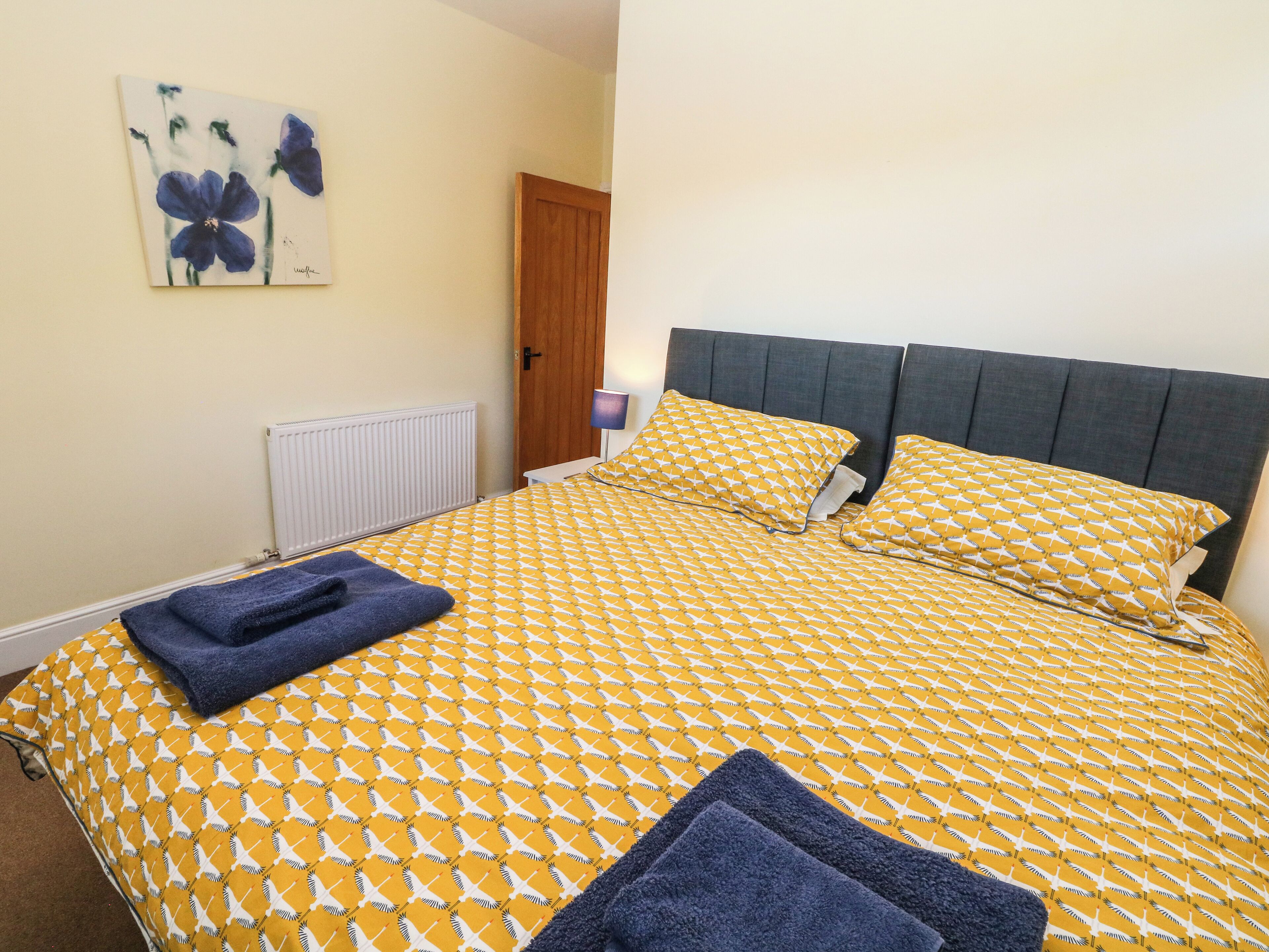 A neatly made bed with a patterned bedspread, two pillows, and two folded towels.