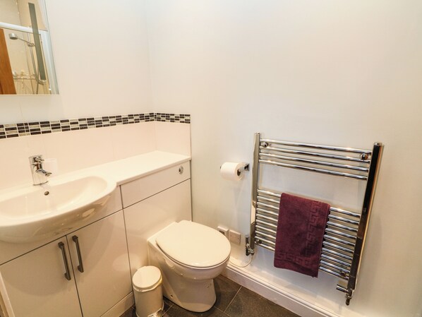 A bathroom with a white sink, toilet, and a towel rack with a towel. - The Barn at Hill House (Buxton)