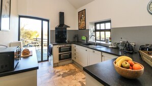 Cozinha moderna com uma janela ampla, forno embutido e uma tigela de madeira com frutas no balcão.