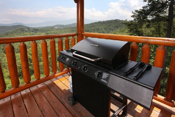 A barbecue grill on a wooden deck with a view of a forested mountain range. - His Amazing Grace (Sevierville)