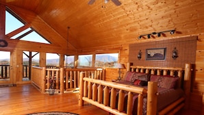 Une chambre située dans un chalet en rondins, avec un lit en bois, de grandes fenêtres et une vue sur les montagnes.
