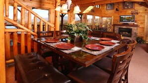 Une salle à manger en bois avec une cheminée, un téléviseur et un escalier.