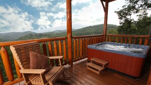 Une terrasse en bois avec un jacuzzi, une chaise berçante et une table.