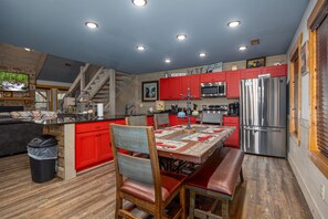 Une cuisine moderne avec des meubles de couleur rouge, des appareils en acier inoxydable et un coin repas comprenant une table et des chaises en bois.