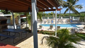 Ein überdachter Außenbereich mit Pool, Liegestühlen und Grillmöglichkeit.