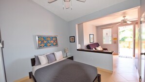 Ein Schlafzimmer mit Bett, Nachttisch, einem Bild und einem Deckenventilator.