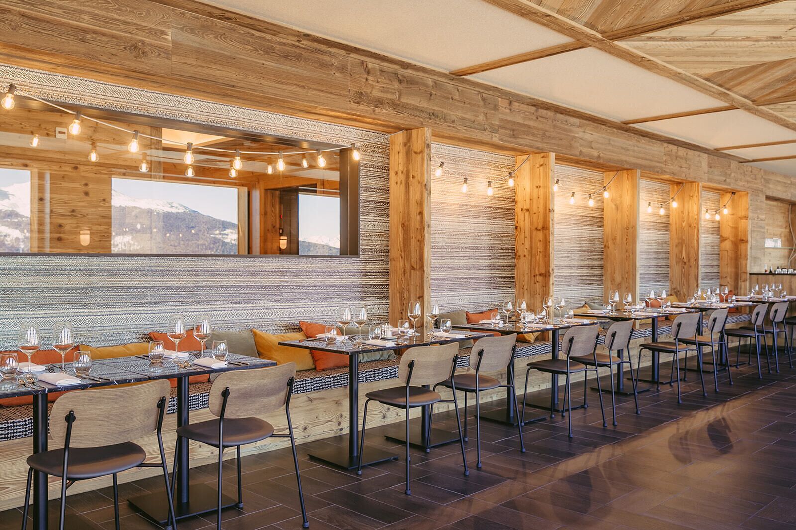 Ein Restaurant mit Holzwänden, großen Fenstern und einem langen Esstisch, gedeckt für mehrere Gäste.