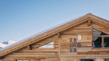 A wooden mountain cabin with a sloped roof, large windows, and a sign reading "ERINGER."