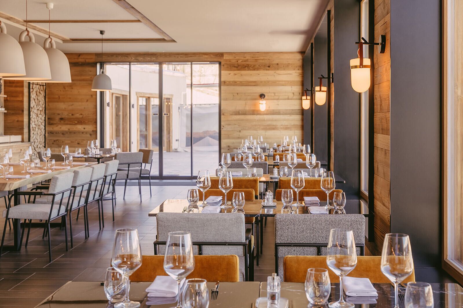 A restaurant with long tables, chairs, and a view of the outside.