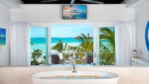 A modern bathroom with a large bathtub, a ceiling fan, and a view of the ocean through large windows. - SulMare at Taylor Bay Luxury Villas (Providenciales)