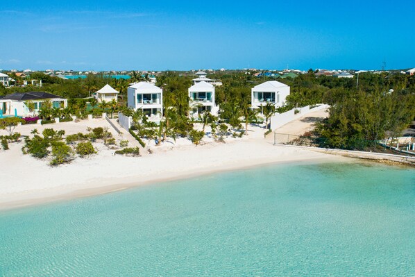 A beachfront property with white buildings, a sandy beach, and clear turquoise water. - SulMare at Taylor Bay Luxury Villas (Providenciales)