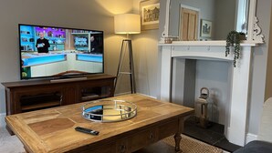Uma sala de estar com uma mesa de centro de madeira, televisão, lareira e espelho.