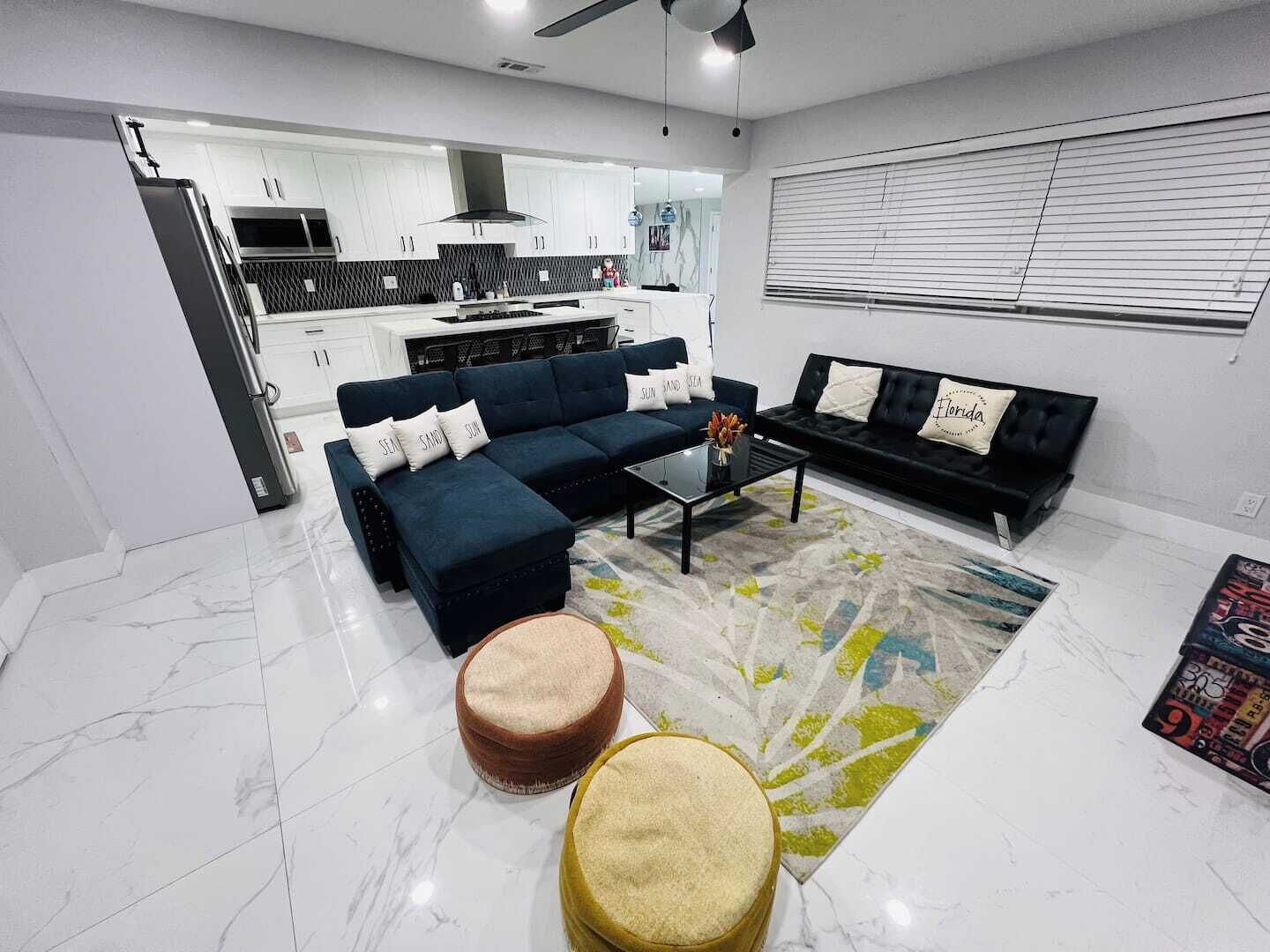 A modern living room with a sectional sofa, a coffee table, and a round ottoman.