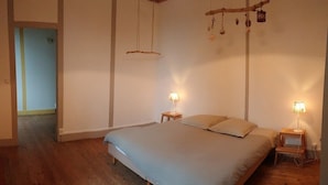 Un dormitorio con una cama grande, suelo de madera y dos lámparas de noche.