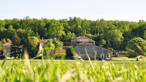 A rural setting with stone buildings surrounded by lush greenery.