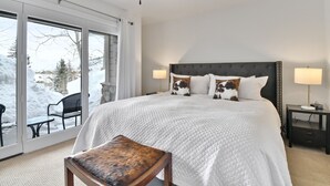 Ein Schlafzimmer mit einem großen Bett, zwei Nachttischlampen, einem Fenster mit Blick auf Schnee und einem Deckenventilator.