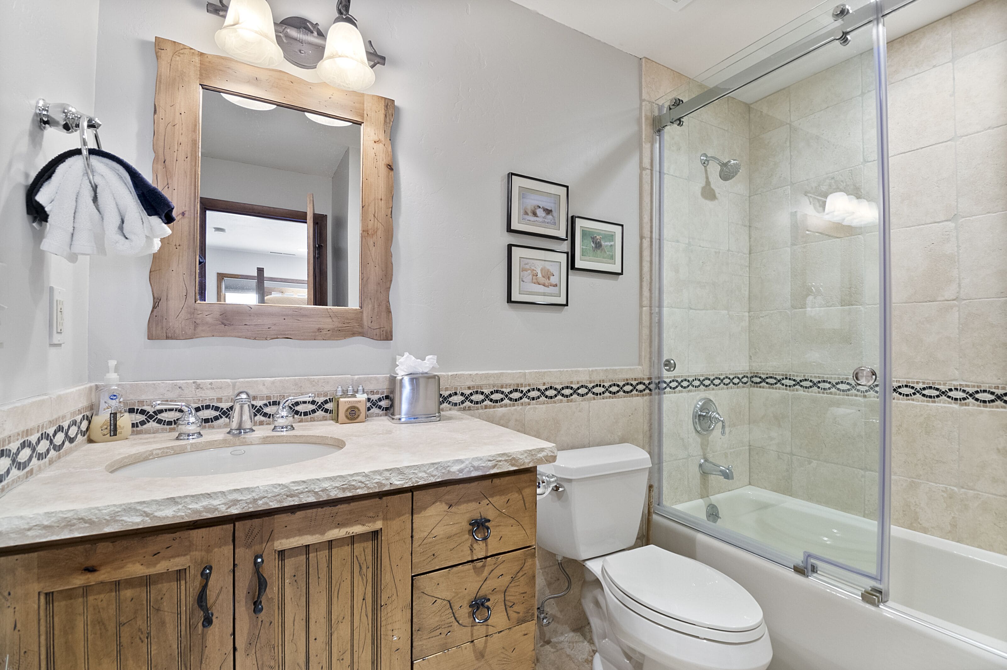 A bathroom with a wooden vanity, a sink, a toilet, and a glass-enclosed shower.