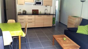 A compact living space with a kitchenette, a dining area with a table and chairs, and a sofa. - T2 recent, air-conditioned, Ideal 50 m from the beach with its private parking space! (Saint-Cyr-sur-Mer)