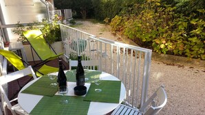 A round table with two wine bottles and glasses, surrounded by white chairs and a white fence. - T2 recent, air-conditioned, Ideal 50 m from the beach with its private parking space! (Saint-Cyr-sur-Mer)