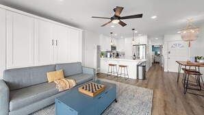 Un salon moderne avec un canapé gris, une table basse bleue et un ventilateur de plafond.