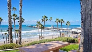 Une vue sur la plage avec une table de pique-nique en bois, des palmiers et une jetée en arrière-plan.