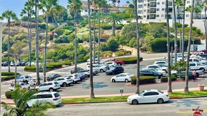 A parking lot with multiple cars, palm trees, and a building in the background. - Oceanview Beach Retreat Walk to Pier AC Pets ok (San Clemente)