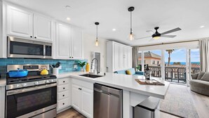 A modern kitchen with white cabinets, a stainless steel stove, and a blue pot. - Oceanview Beach Retreat Walk to Pier AC Pets ok (San Clemente)