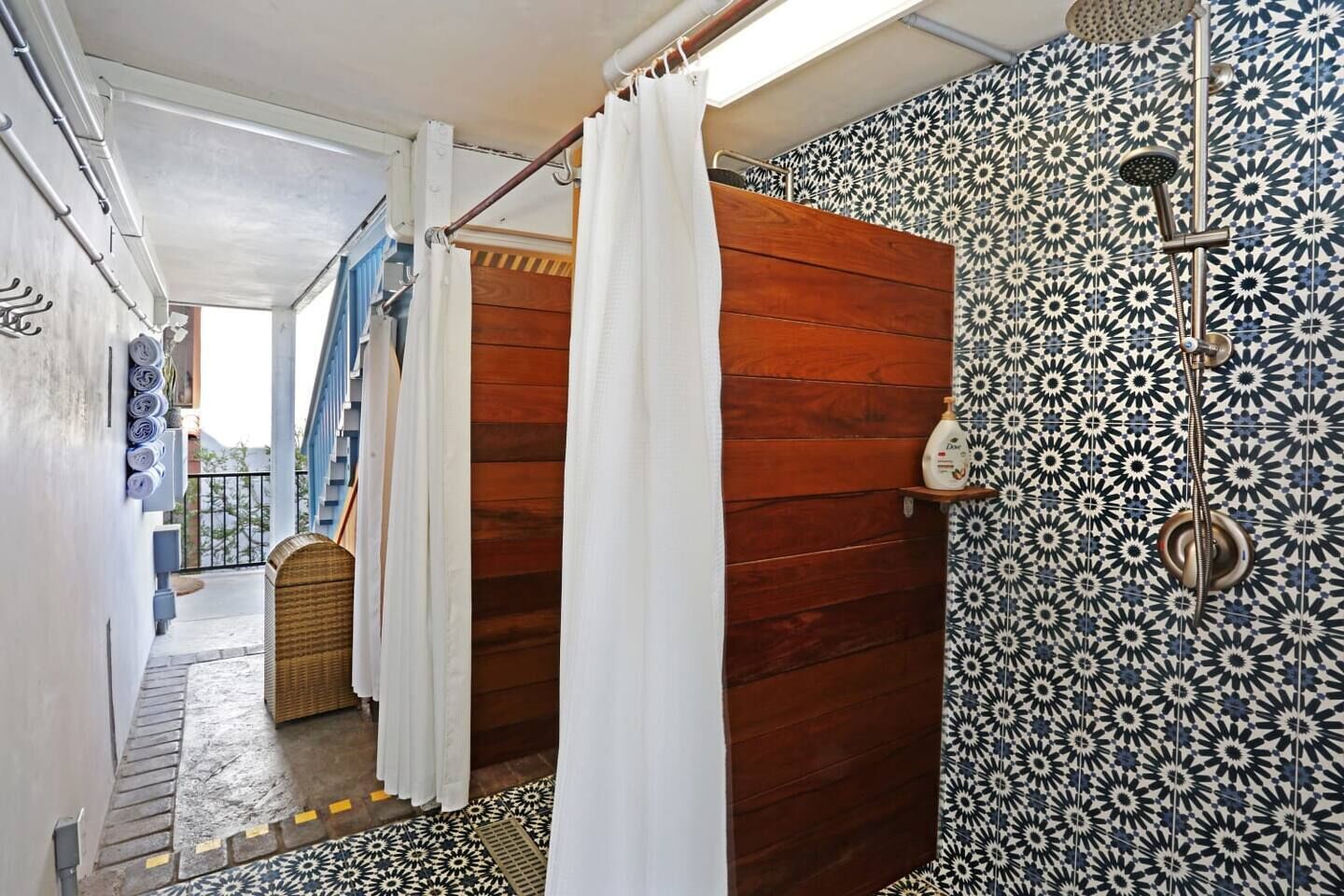Une salle de bain avec une douche, des carreaux décorés et une porte en bois.