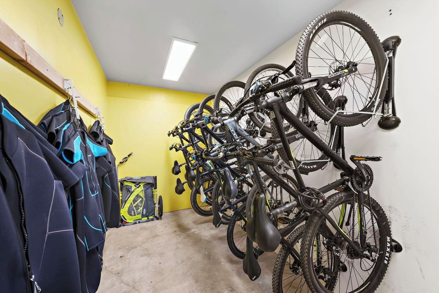 Una stanza con pareti gialle, una luce a soffitto e un portabici con diverse biciclette.