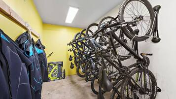 Una stanza con pareti gialle, una luce a soffitto e un portabici con diverse biciclette.