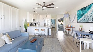 A modern living room with a sofa, coffee table, and a dining area with bar stools.