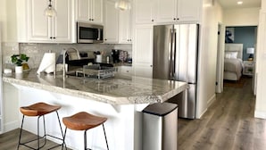 A modern kitchen with white cabinetry, stainless steel appliances, and a granite countertop.