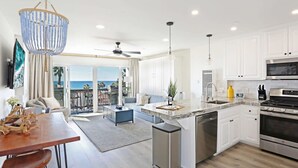 A modern kitchen with white cabinets, stainless steel appliances, and a large island.