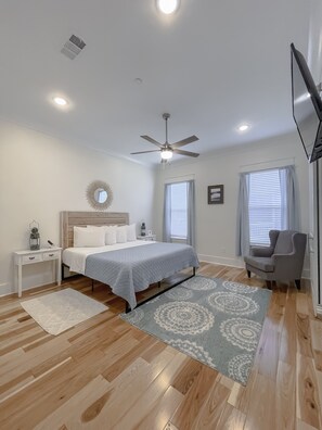Relax in a serene space with a large bed, ceiling fan, and flat-screen TV.