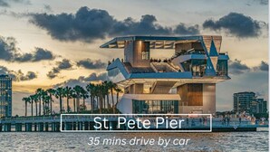 A modern waterfront hotel with a unique architectural design, featuring multiple levels and balconies, located near a pier with palm trees. - MODERN/Mins to Beach/walk to dwtn/Free parking (Tarpon Springs)